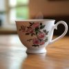 A ceramic tea cup sitting on a saucer, filled with steaming tea. The cup has a delicate handle and a simple, elegant des